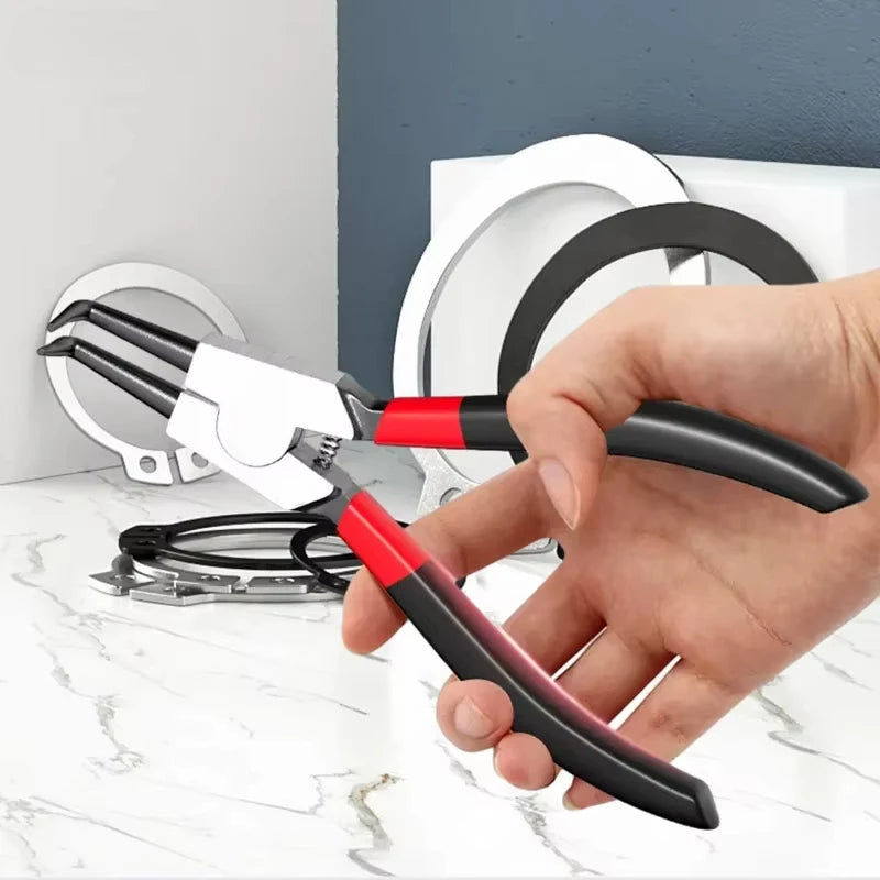 A hand holds a pair of black and red dual-use circlip pliers against a white retaining ring.