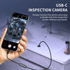 A hand holds a smartphone connected to a USB-C inspection camera, which is pointed at a bathroom fixture.