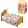 A yellow wooden bed with pink and green patterned bedding and a matching box for Sylvanian Families Forest Friends.