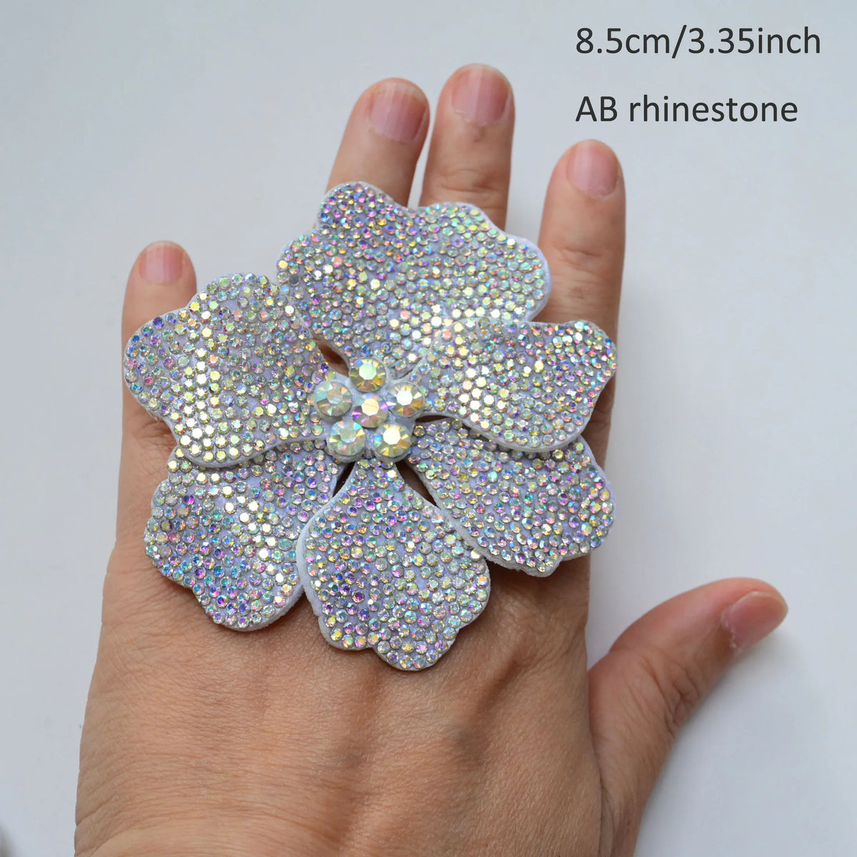 Silver rhinestone flower sew-on patch displayed on a hand for scale.