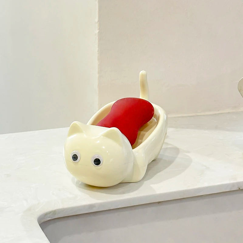 A white cat-shaped soap box with a red drainage tray sits on a white surface.