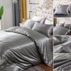 Silver silky duvet cover set featuring corner ties and a zipper on a bed with a tufted headboard
