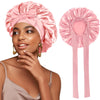 A woman models a pink satin sleeping bonnet with an adjustable tie.