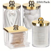 A set of three elegant apothecary jars with golden lids for storing cotton balls and swabs.