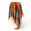 A vibrant orange and blue leopard paisley square scarf draped on a white surface.