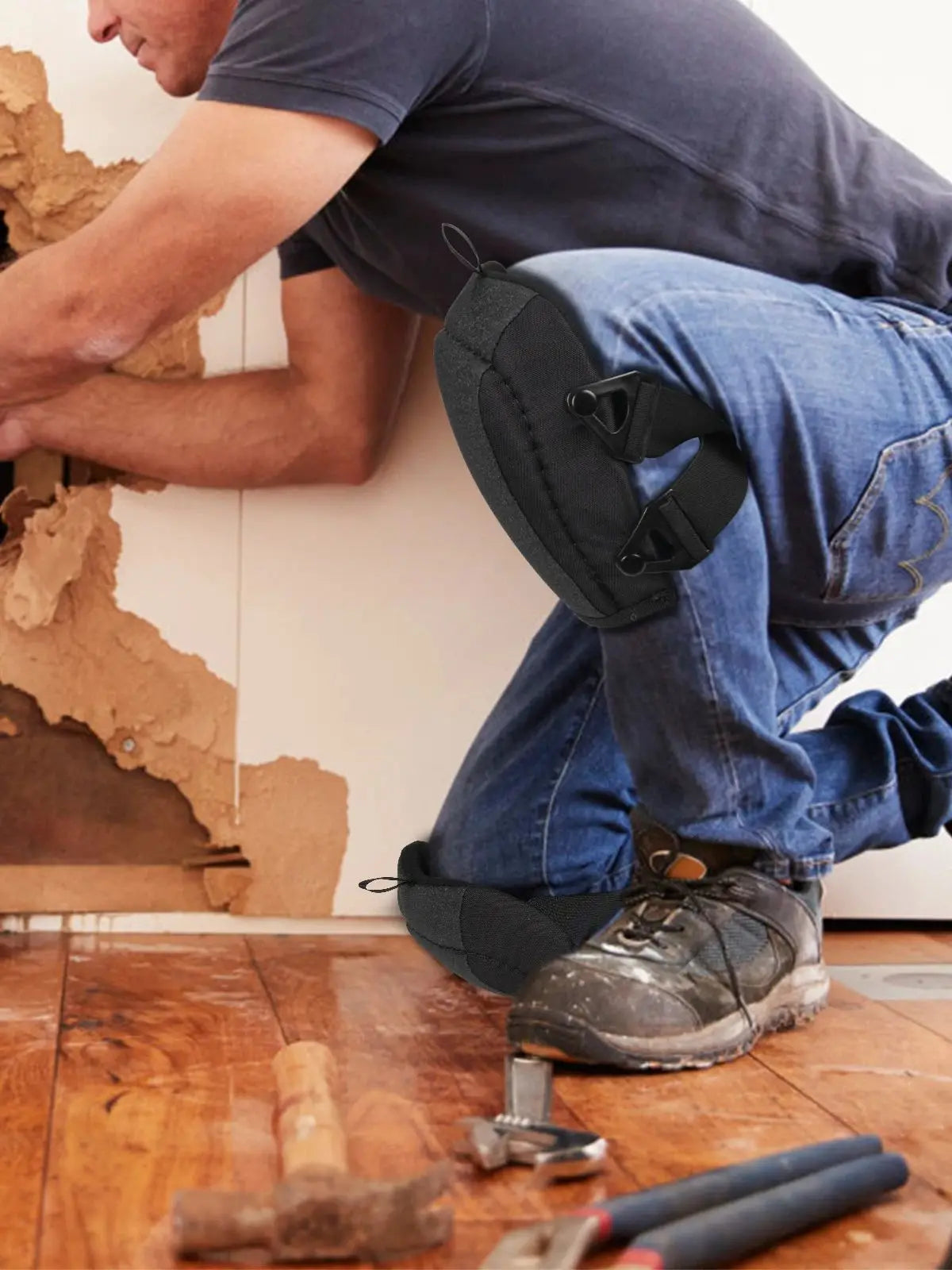 A person wearing dark t-shirt and jeans is kneeling while working, with black non-slip knee pads visible on their legs.