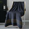 A dark gray luxury bath towel draped over a white stand with gold accents.