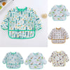 A collection of light green and white kids waterproof long sleeve smocks and feeding bibs featuring various nature-themed pat