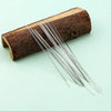 A bundle of stainless steel beading needles is laid out on a piece of dark wood.