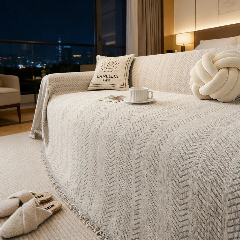 A beige anti-slip sofa cover featuring a fishbone pattern on a two-seat sofa.