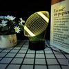 A yellow sports-themed night light with a mesh pattern sits next to a potted white flower plant.