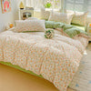 A floral duvet cover set featuring light pink and green patterns on a bed with matching pillows.