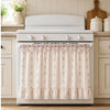 A white farmhouse oven skirt with a floral pattern and ruffle trim is installed below a white stove top.