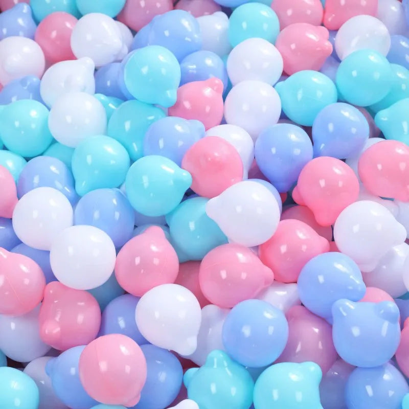 A pile of colorful non-toxic ball pit balls in shades of pink, blue, and white for children.