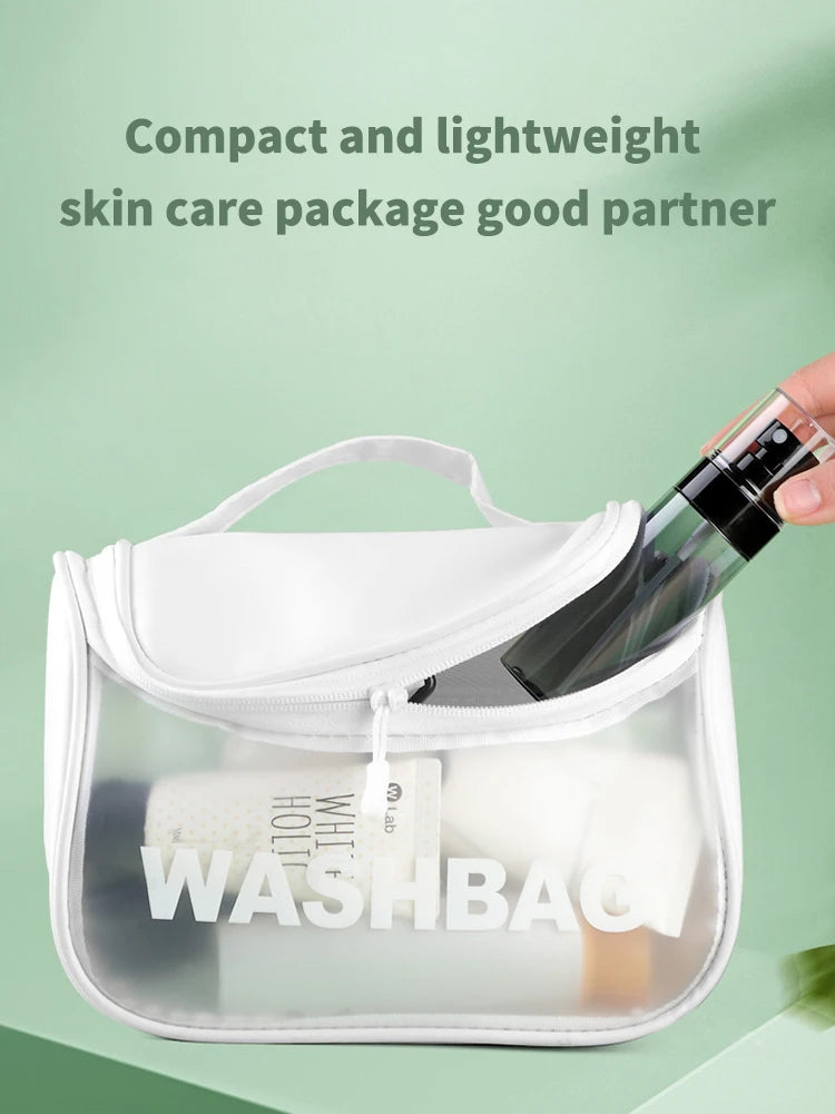 A clear plastic cosmetic pouch containing a refillable travel spray bottle and white cotton pads for skincare.