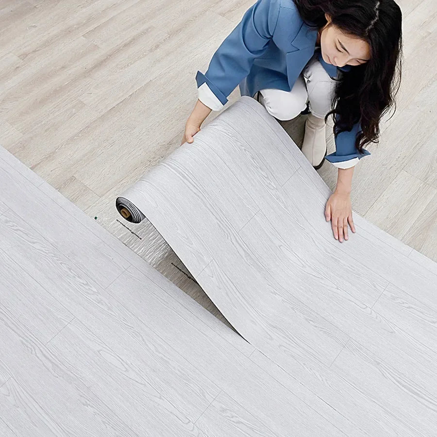 A young woman is carefully peeling a roll of white wood grain peel and stick wall decals.