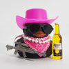 A black rubber duck shaped like a cowboy wearing a pink hat and sunglasses, next to a bottle of Corona Extra.