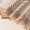 Close-up of a beige woven fabric sofa cover featuring handmade woven tassels and a fishbone pattern.