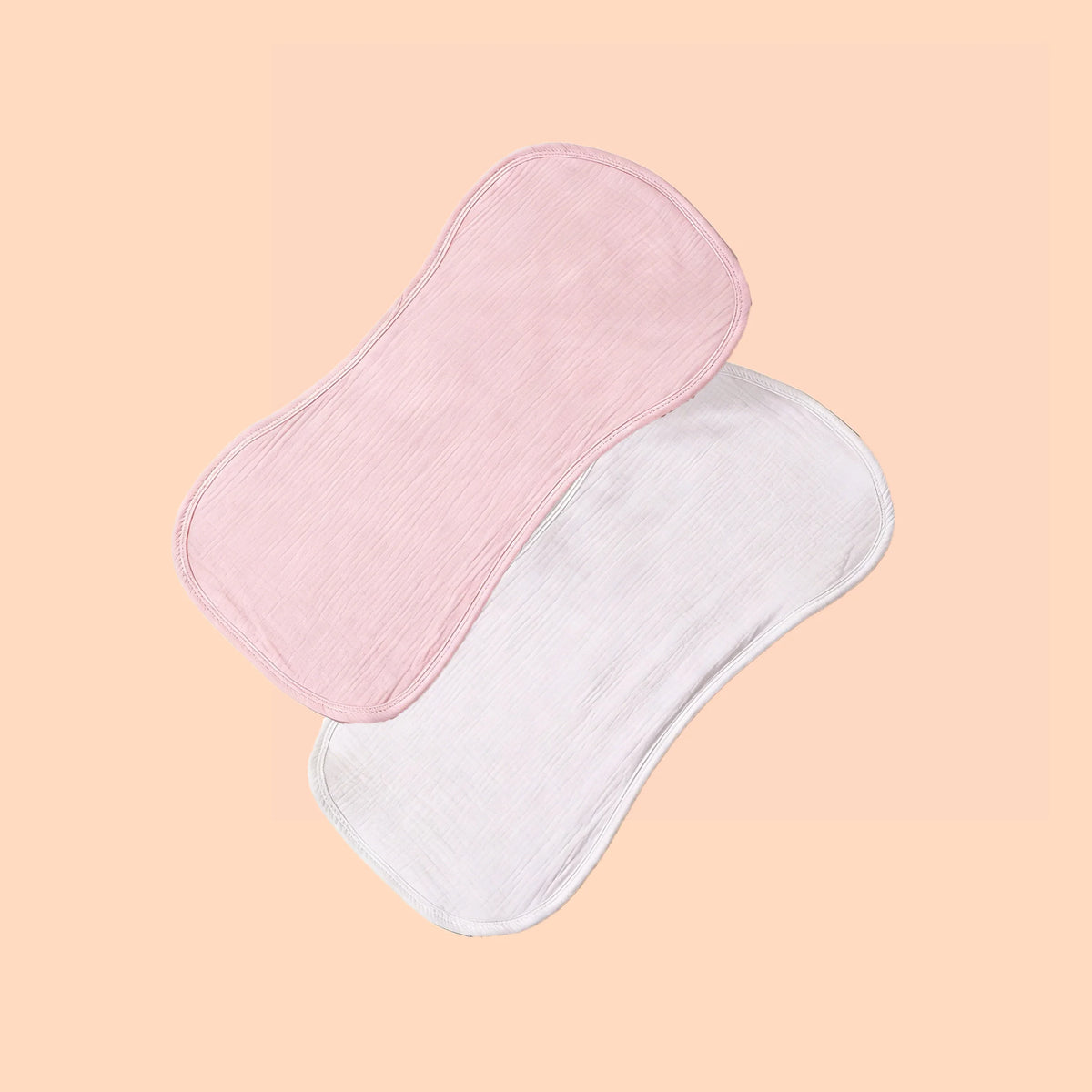 A pair of pink and white multi-use baby burp cloths are shown against a light peach background.