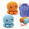 A DIY crochet kit showing a finished orange animal and a light blue plant-like creature with yarn and a needle.