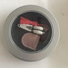 A pair of small white precision mini scissors with a protective cover and a red cord are visible inside a silver container.