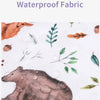Close-up of a brown bear illustration on a white fabric featuring water droplets and green foliage.