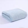 Light blue knitted bath towel folded neatly on a white surface