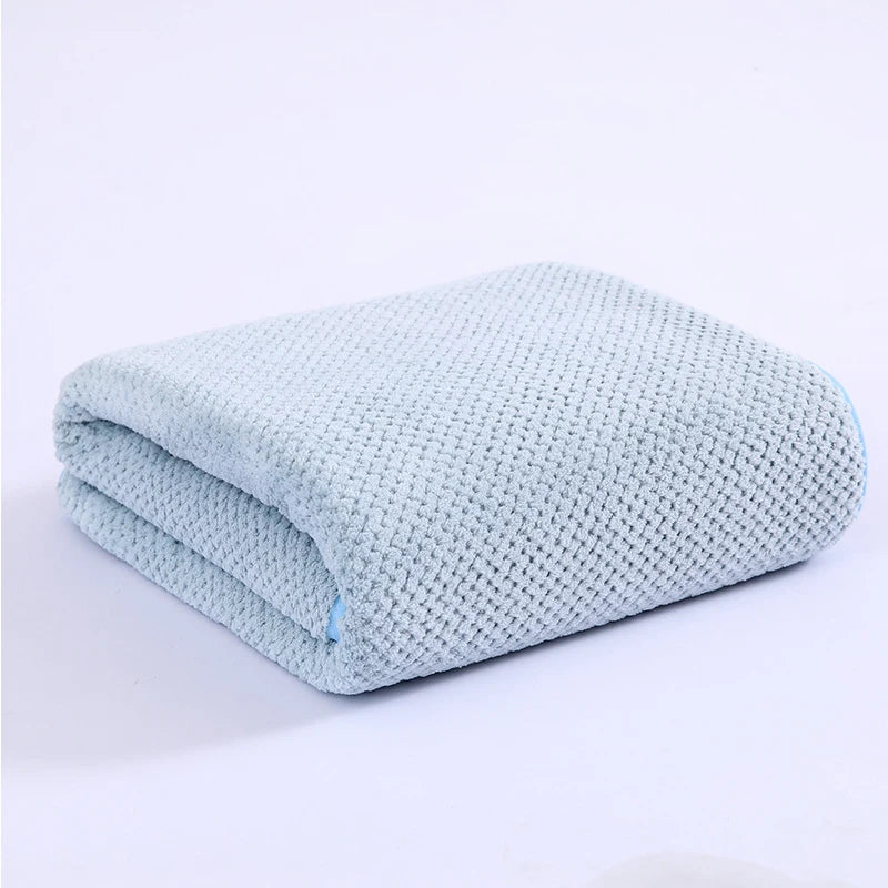 Light blue knitted bath towel folded neatly on a white surface