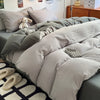 A close-up of a light gray duvet cover set featuring soft, textured fabric and a small stuffed animal on a bed.