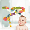 A baby is looking up at a colorful bath time duck slide toy set with various colored plastic components.