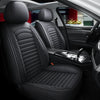 Interior view of a car showing black leather seats with quilted stitching and a driver's door panel.