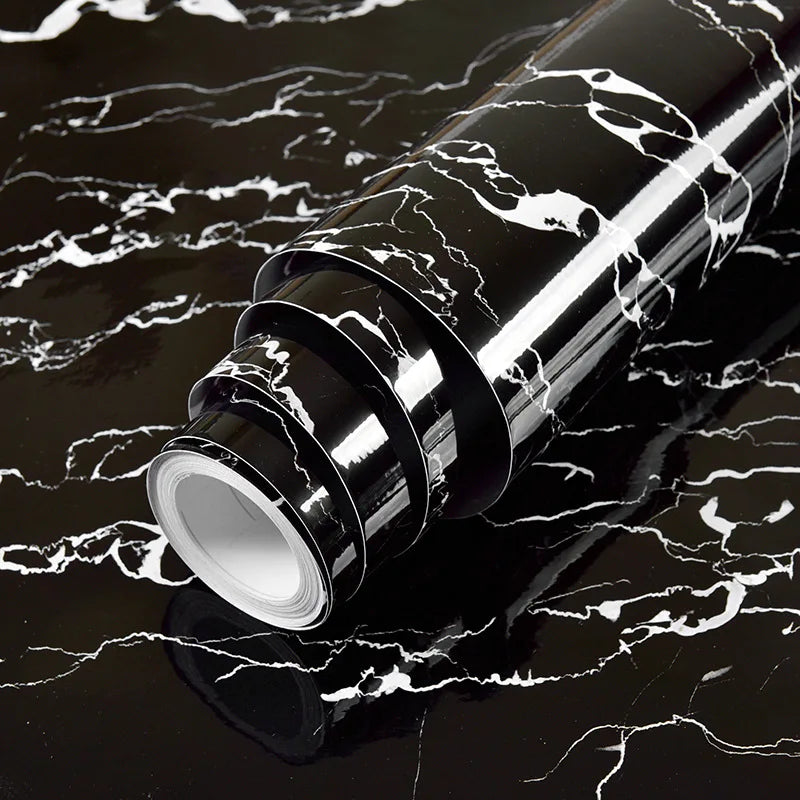 Roll of waterproof self-adhesive marble wallpaper with black and white veining on a dark surface