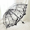 A transparent umbrella with a black frame features a silhouette design of various animals and trees.
