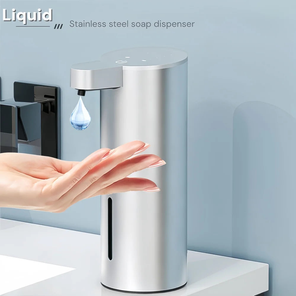 A hand is dispensing liquid soap from a stainless steel touchless automatic dispenser.