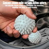A hand is holding a white concave convex spike sphere laundry ball inside a washing machine drum.