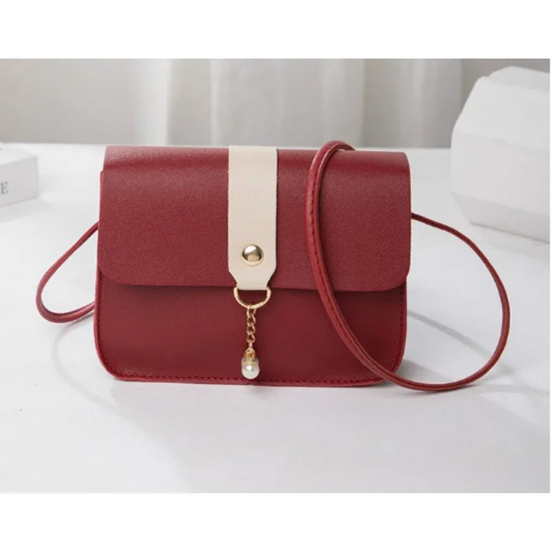 A maroon compact crossbody handbag with a light beige strap and gold chain detail.
