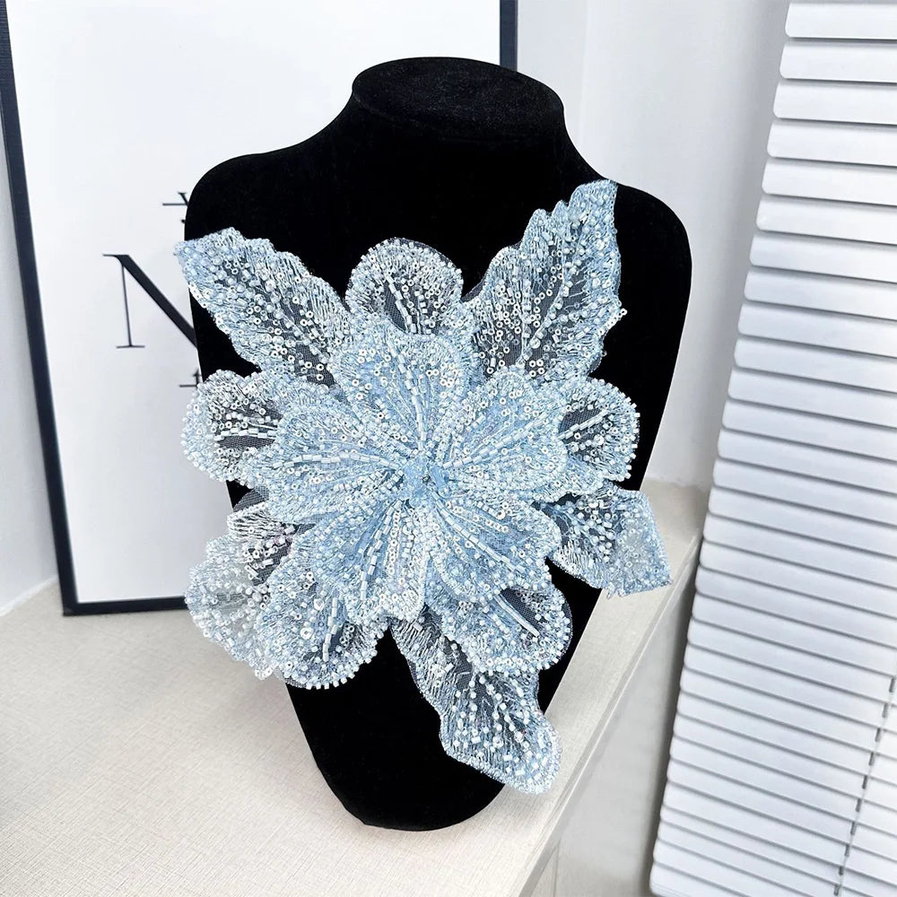 A light blue floral lace applique patch made of sequins displayed on a black mannequin.
