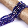 A strand of deep blue faceted crystal glass spacer beads is unwrapped on a gold-colored paper roll.