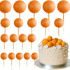 Mehrstöckiger Kuchen mit orange-weißen Kugeln auf Stäbchen.