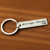 Silver stainless steel keychain with engraved text drive safe i love you and a heart symbol on a brown fabric background