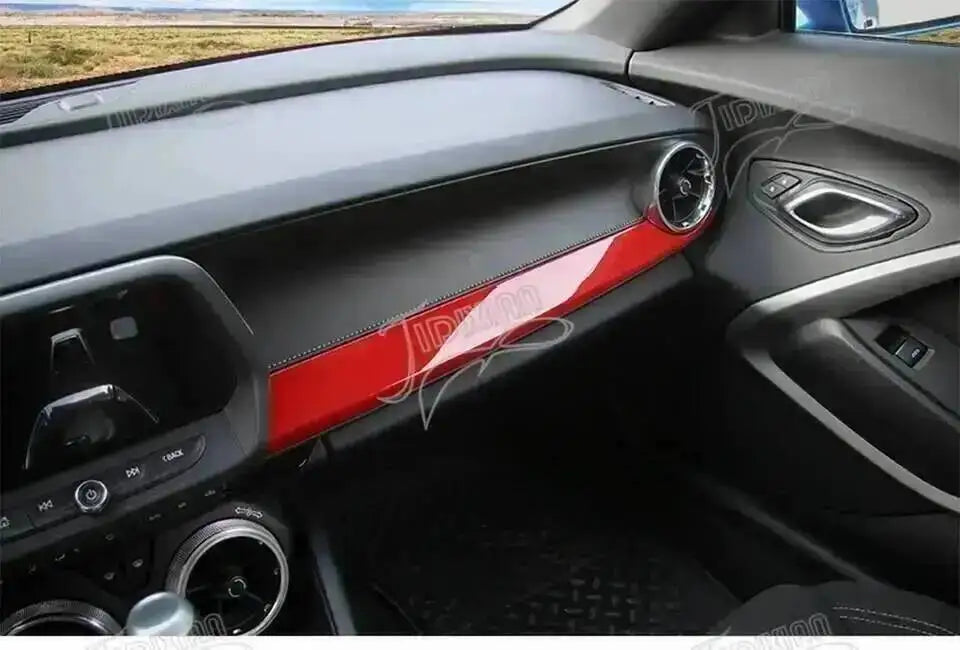 Interior view of a car with red trim accents on the dashboard and door panel.