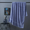 A soft lavender bath towel hanging on a rack against a gray wall.