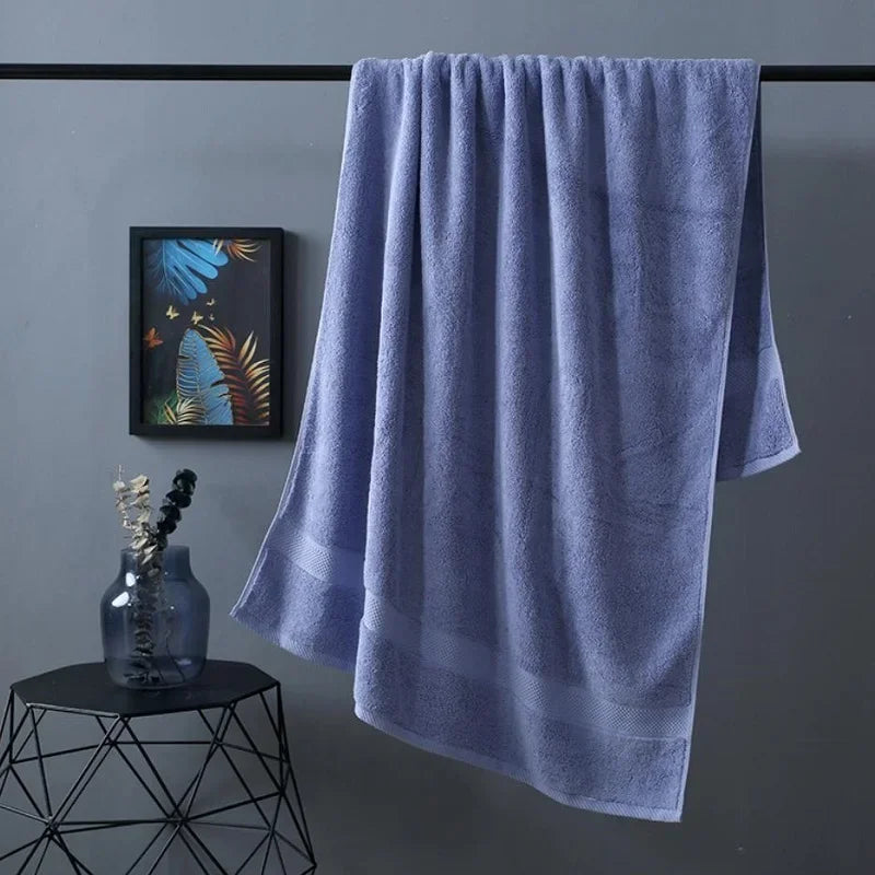 A soft lavender bath towel hanging on a rack against a gray wall.
