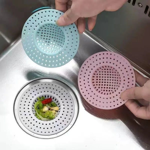 A hand is placing a pink silicone sink drain filter strainer onto a stainless steel sink drain.