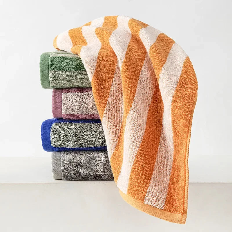 A stack of soft plaid cotton bath towels in shades of orange, green, purple, and blue.