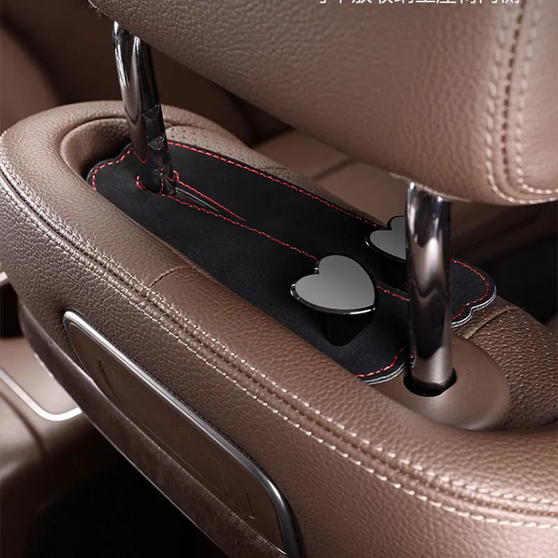 A close-up of a car seat headrest with dual metal hooks designed for hanging bags or phones.