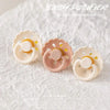 A set of light pink and white silicone baby pacifiers with a glow-in-the-dark feature displayed on a white background.