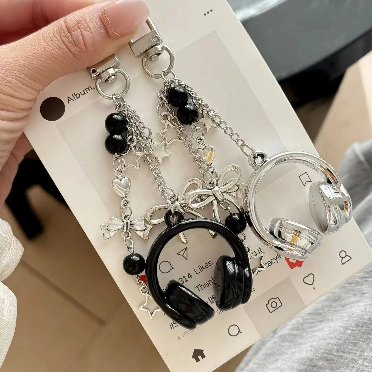 Silver metal music note charms hanging from chains displayed on a white card.