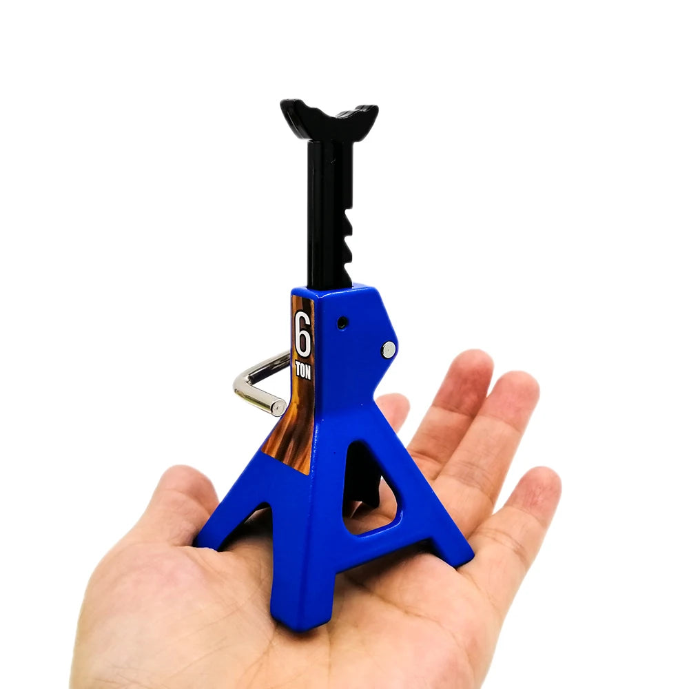 A blue metal RC jack stand with a black scissor-style lifting tool is held in a hand.