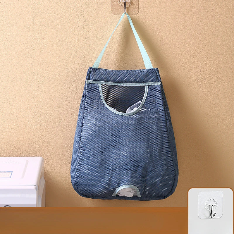 A dark blue mesh garbage bag holder is hanging on a wall, featuring a fabric pouch and hooks.
